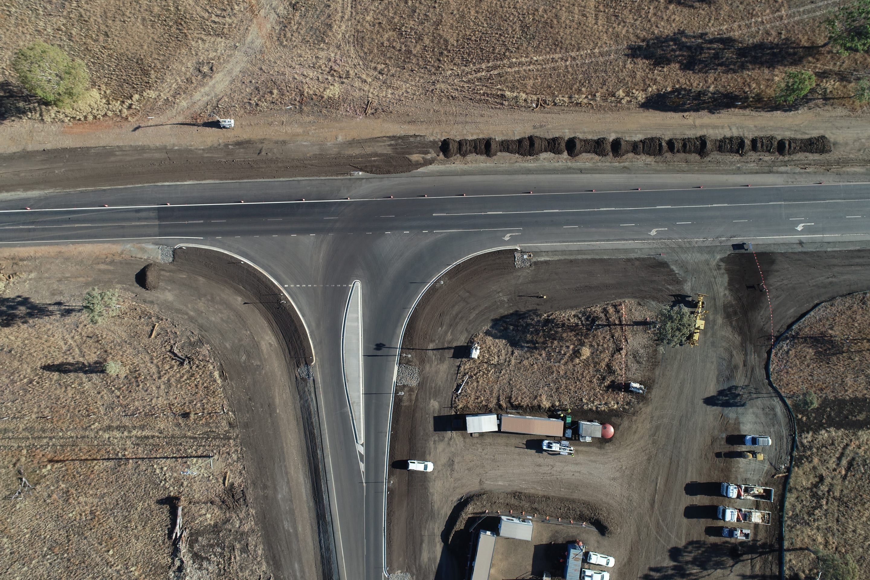Aerial view of a new T-intersection on a highway, with the site compound and plant beside it