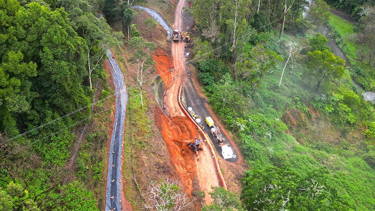Aerial view of flood restoration works on a road cut through a forested hillside
