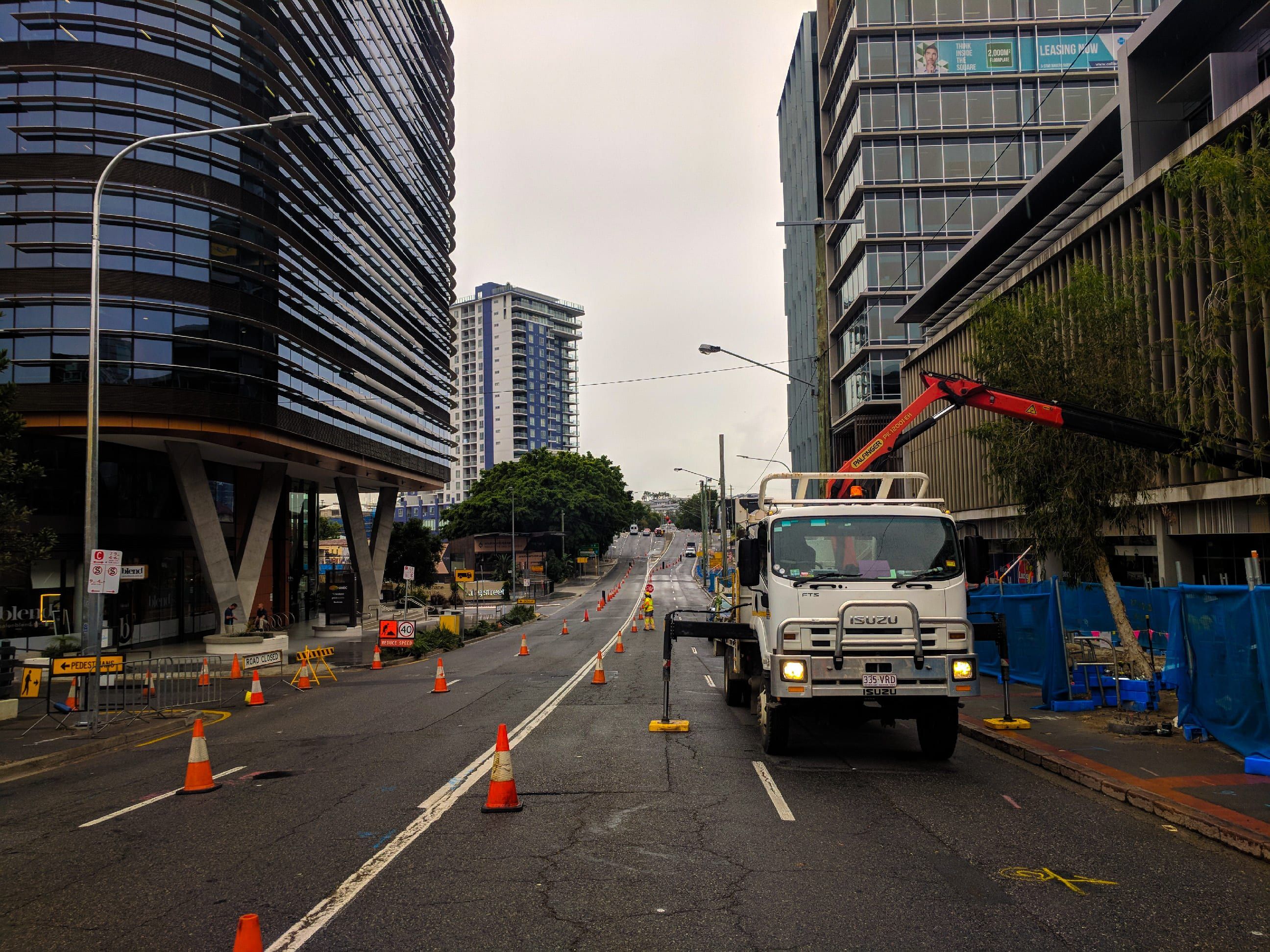 Truck working in a coned-off lane of a city road under traffic