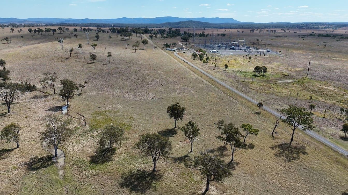Aerial view of open grazing land beside the Teebar Creek substation, with ranges in the distance